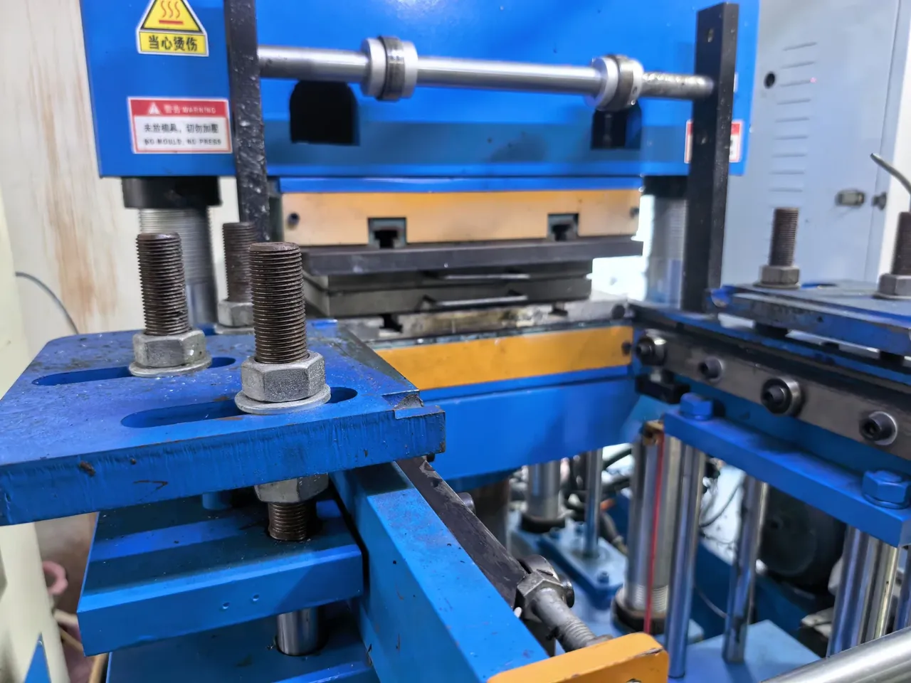 Blue compression molding equipment in the supplied workshop photograph