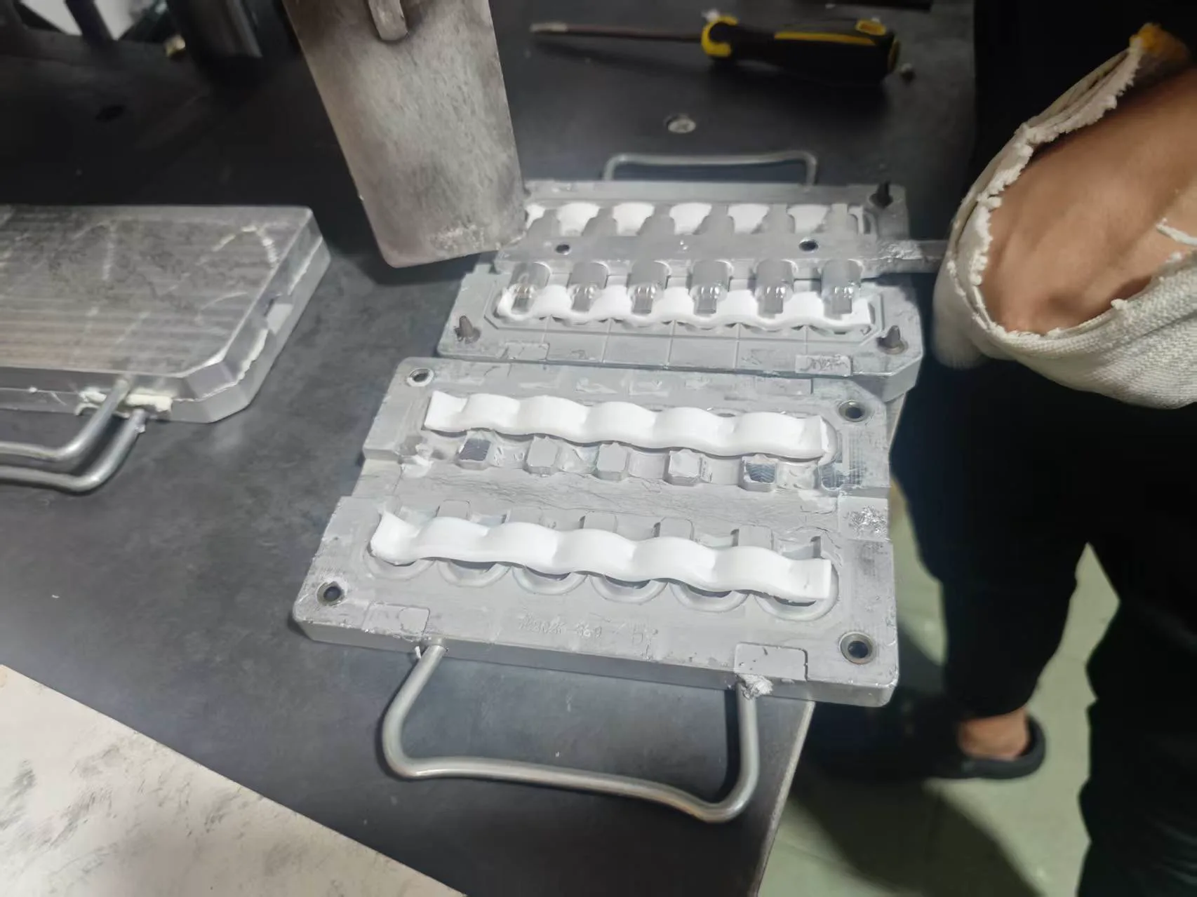 White silicone compound placed in a metal mold before compression molding in the workshop