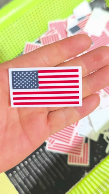 A white-base silicone flag patch held by hand in the workshop